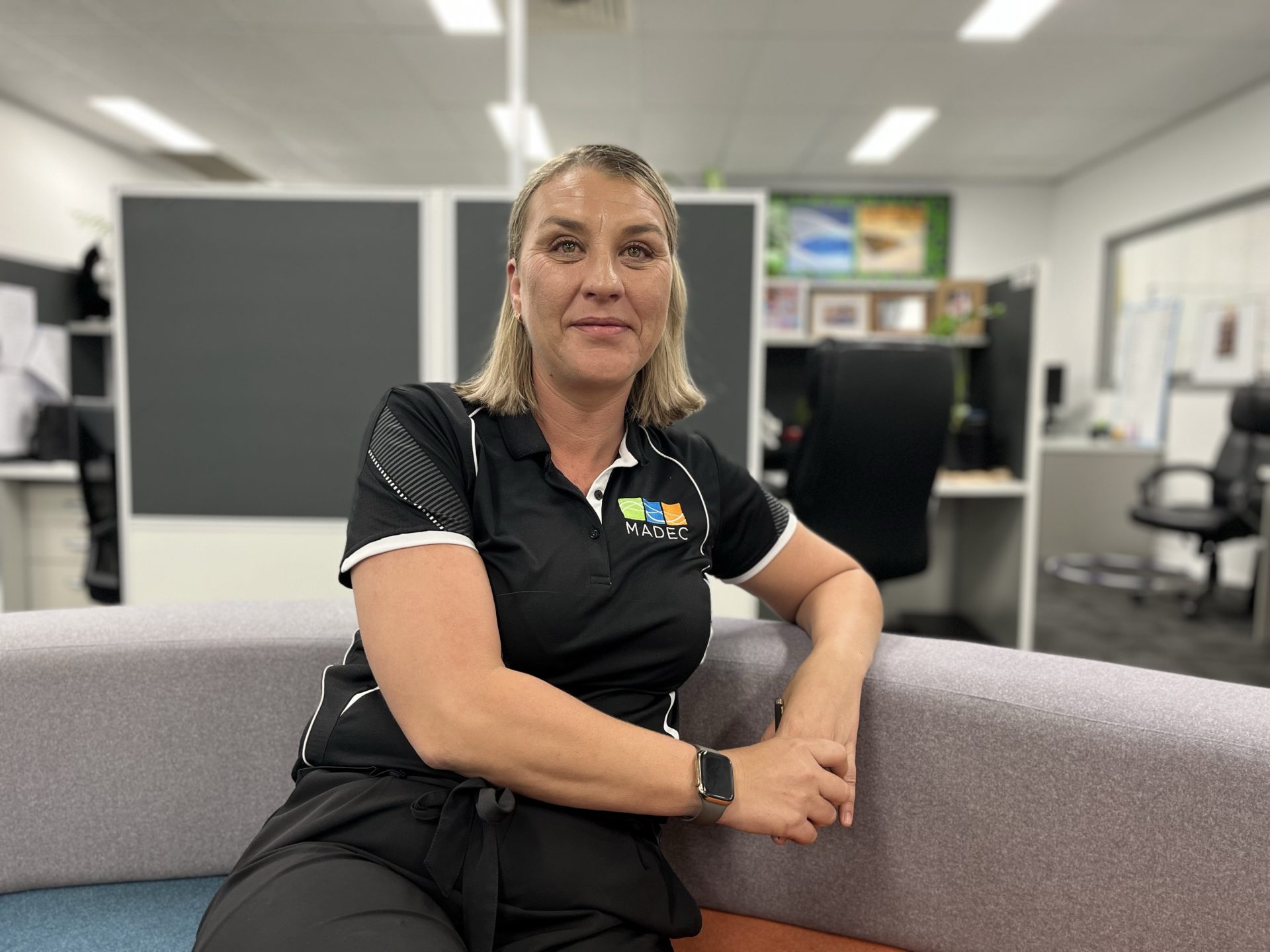 Bernhardette Lishman, MADEC's Strategic Quality Manager, sits on a couch in the MADEC office.